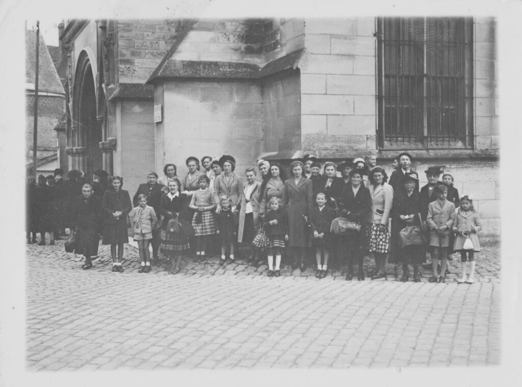 Des familles de La Romagne à la sortie de messe à Notre-Dame-de-Bon-Secours à Neuvizy (Ardennes), lors d'un pèlerinage, photographie ancienne en noir et blanc, collection privée, avec l’aimable autorisation de madame Reine Druart †.
