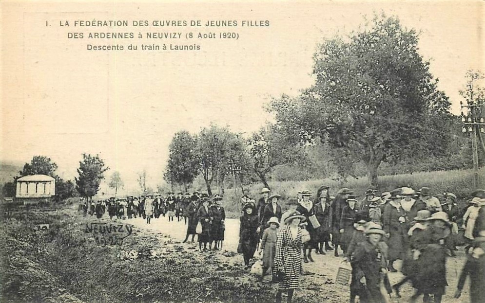 La fédération des œuvres de jeunes filles descend du train le dimanche 8 août 1920 à Launois-sur-Vence (Ardennes) pour se rendre au pèlerinage de Neuvisy (Ardennes). Carte postale ancienne en noir et blanc.