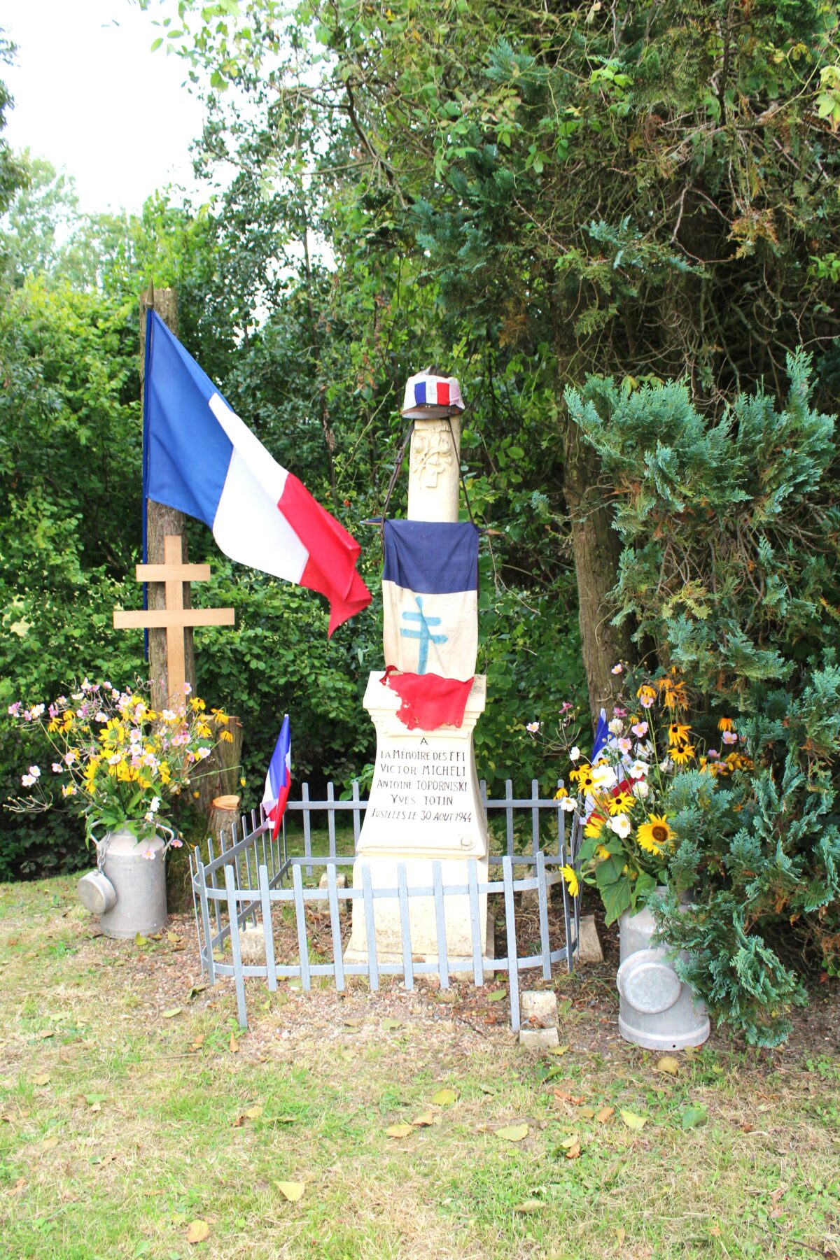 Stèle des fusillés, lors de la cérémonie du quatre-vingtième anniversaire. En matière de symbolique funéraire, la colonne brisée (ou tronquée) est un élément funéraire choisi pour honorer des personnes décédées prématurément et dans la force de l’âge. Prise de vue effectuée le vendredi 30 août 2024 à Wadimont (Ardennes). Crédits photographiques : © 2020 laromagne.info par Marie-Noëlle ESTIEZ BONHOMME.