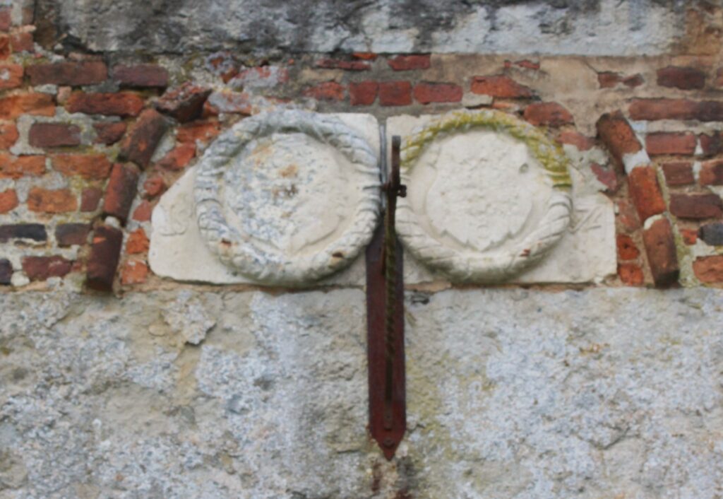 L'effacement des armoiries sur la façade est du château de Rocquigny (Ardennes) rend difficile leur identification et leur rattachement à une famille précise. Le passage du temps, l'usure des matériaux et l'exposition aux intempéries ont contribué à l'altération de ces éléments héraldiques, laissant des traces vagues et indistinctes. Photographie en couleurs, prise de vue effectuée le vendredi 18 octobre 2024. Crédits photographiques : © 2020 laromagne.info par Marie-Noëlle ESTIEZ BONHOMME.