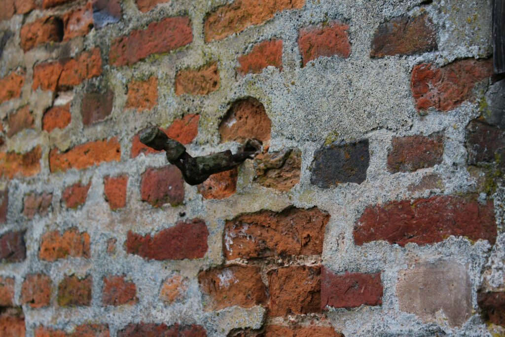 L'attache de volet sur la façade sud du château de Rocquigny (Ardennes) est un élément de ferronnerie encore en place malgré l'usure du temps. Photographie en couleurs, prise de vue effectuée le mercredi 18 décembre 2024. Crédits photographiques : © 2020 laromagne.info par Marie-Noëlle ESTIEZ BONHOMME.