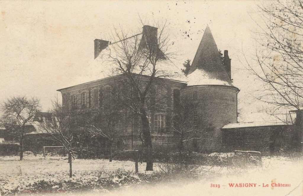 Les arbres dénudés, alourdis par l’enneigement, encadrent la silhouette du château de Wasigny (Ardennes). Archives départementales des Ardennes, 8Fi 11 [série Fi = documents figurés et assimilés entrés par voie extraordinaire, sous-série 8Fi = cartes postales], carte postale ancienne en noir et blanc consultable en ligne.