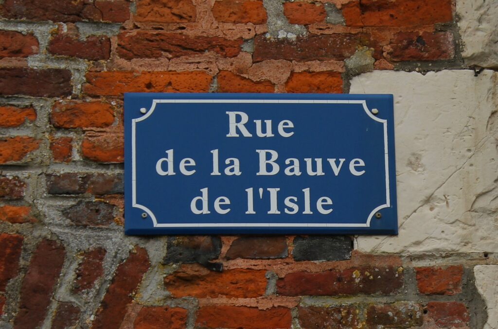 Plaque de la rue de La Bauve de l'Isle, du nom de la famille qui fut longtemps propriétaire du château de Rocquigny (Ardennes). Cette dénomination rend hommage à l’influence et à l’ancrage historique de cette lignée dans la région. Témoignage du passé du domaine, elle perpétue le souvenir de ceux qui ont marqué l’histoire locale. Photographie en couleurs, prise de vue effectuées le mercredi 18 décembre 2024. Crédits photographiques : © 2020 laromagne.info par Marie-Noëlle ESTIEZ BONHOMME.