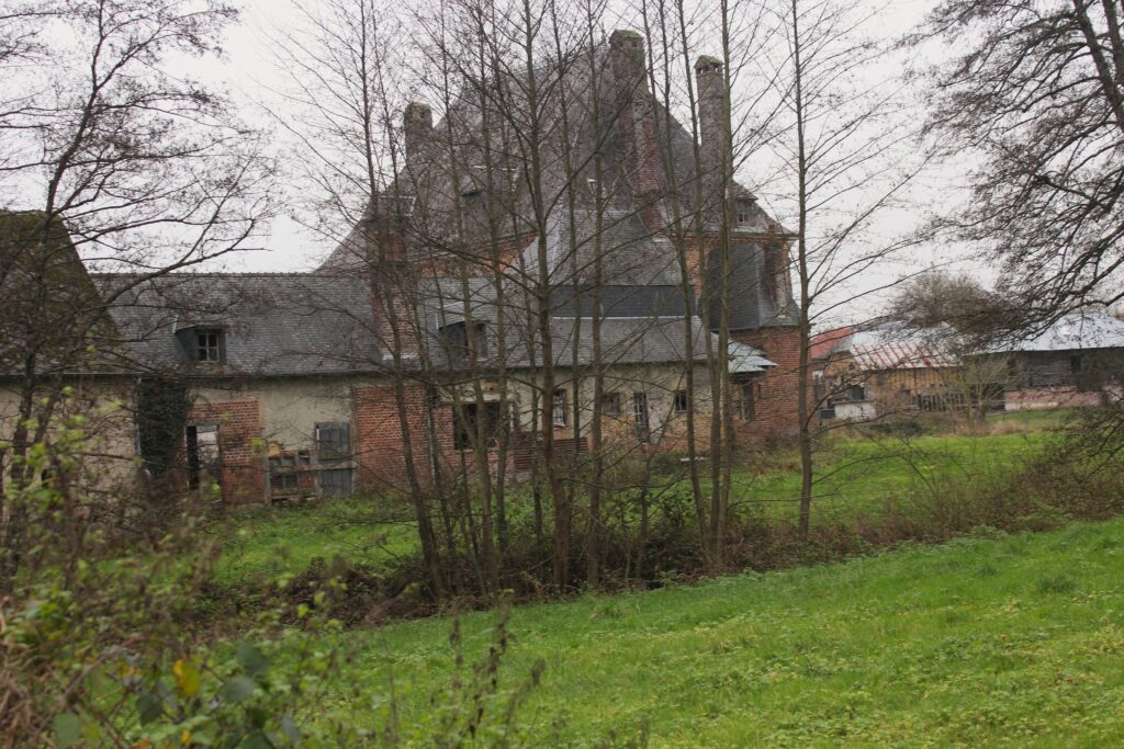 Façade nord du château de Rocquigny (Ardennes), avec une vue qui s’ouvre sur les communs partiellement dissimulée derrière un rideau d’arbres. Photographies en couleurs, prises de vue effectuées le jeudi 12 décembre 2024. Crédits photographiques : © 2020 laromagne.info par Marie-Noëlle ESTIEZ BONHOMME.