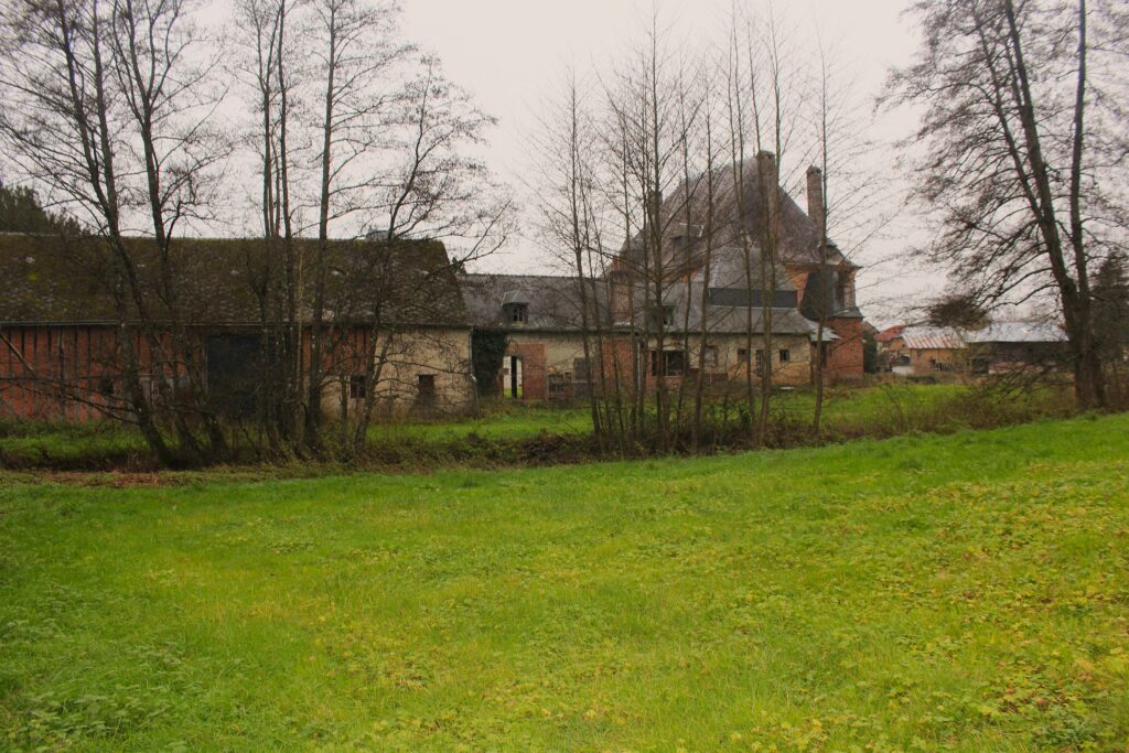 Façade nord du château de Rocquigny (Ardennes), avec une vue qui s’ouvre sur les communs partiellement dissimulée derrière un rideau d’arbres. Photographies en couleurs, prises de vue effectuées le jeudi 12 décembre 2024. Crédits photographiques : © 2020 laromagne.info par Marie-Noëlle ESTIEZ BONHOMME.