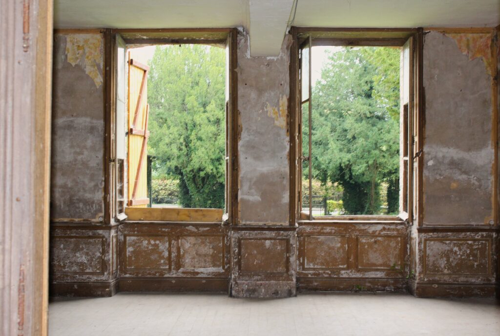 Petit salon à droite de l'entrée, communiquant avec la salle à manger, au rez-de-chaussée du château de Rocquigny (Ardennes). De grandes fenêtres offrent une vue dégagée sur la rue de La Bauve de l'Isle, tout en offrant un aperçu de l’ancien jardin qui orne la façade est. Photographie en couleurs, prise de vue effectuée le vendredi 18 octobre 2024. Crédits photographiques : © 2020 laromagne.info par Marie-Noëlle ESTIEZ BONHOMME.