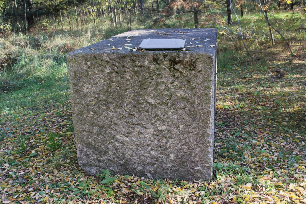 „Die beiden hier verwendeten Granitblöcke wurden 2011 am Ufer des Oder-Spree-Kanal in Eisenhüttenstadt geborgen. Dort überdauerten sie als Rest eines Steinvorrats, der während des Zweiten Weltkriegs für ein von Hitler in Berlin geplantes Bauvorhaben der Deutschen Wehrmacht angelegt wurde, den Neubau des Oberkommandos des Heeres mit der sogenannten „Soldatenhalle". Um hochwertige Natursteine für dieses Bauprojekt einzulagern, entstand ab 1940 eigens eine Hafenanlage unmittelbar südlich des Stalag III-B. Beim Aushub des 400 Meter langen Hafenbeckens wurde ein Kommando französischer Juden aus dem Kriegsgefangenlager eingesetzt. Auf dem Hafengelände wurden etwa 20 000 Kubikmeter Großquader gestapelt, darunter Granit aus Skandinavien und aus den Steinbrüchen der SS, wo KZ-Häftlinge unter mörderischen Bedingungen Zwangsarbeit leisteten. Nach Kriegsende nutzte unter anderem die sowjetische Besatzungsmacht den Steinvorrat, so zum Bau der Ehrenmale in Berlin-Treptow und auf dem Platz des Gedenkens in Eisenhüttenstadt.“
Photographie en couleurs, prise de vue effectuée le vendredi 25 octobre 2024. Crédits photographiques : © 2020 laromagne.info par Marie-Noëlle ESTIEZ BONHOMME.