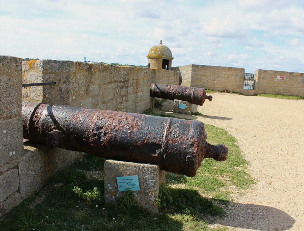 Canons du Juste, vaisseau français échoué près de Saint-Nazaire après la bataille des Cardinaux (1759). Dépôt du Département des recherches archéologiques subaquatiques et sous-marines (DRASSM). Echauguette à l’arrière-plan. Photographie en couleurs, prise de vue effectuée le jeudi 17 avril 2025 à la citadelle de Port-Louis (Morbihan). Crédits photographiques : © 2020 laromagne.info par Marie-Noëlle ESTIEZ BONHOMME.