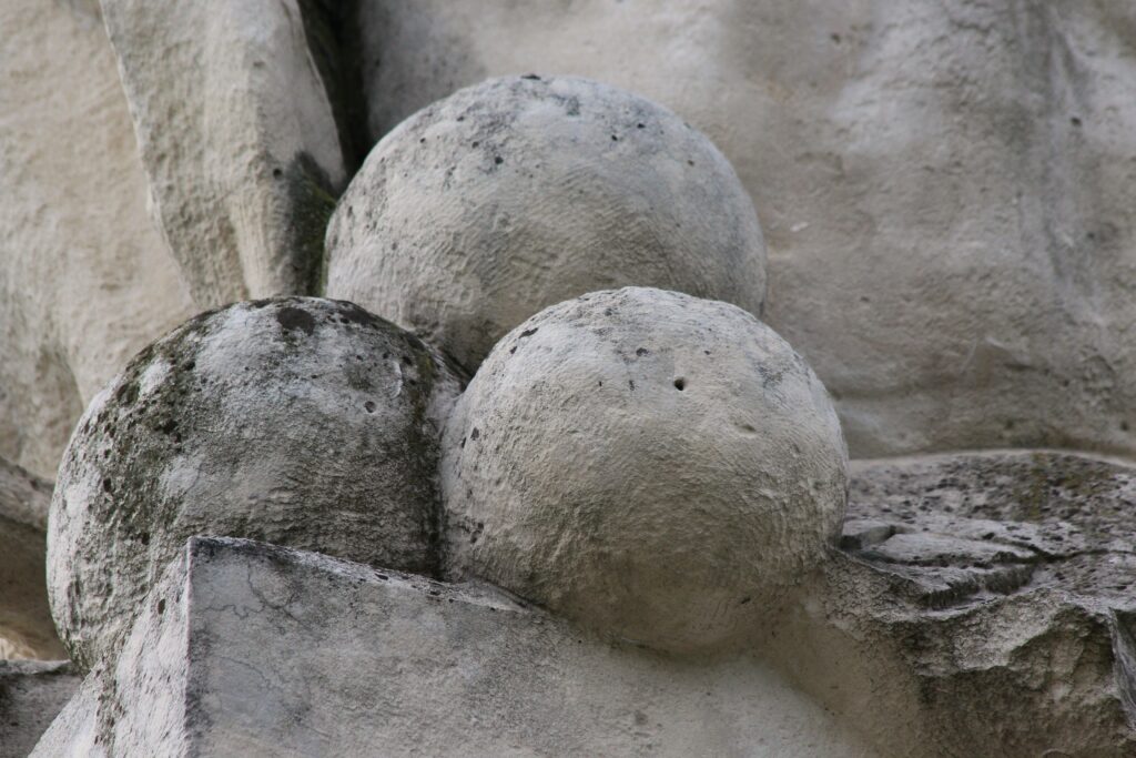 Trois boulets. [Nota bene : la balistique historique, science auxiliaire de l’histoire militaire étudie les projectiles anciens (boulets, balles, grenades), leur fabrication, leur typologie, leur emploi et leurs effets.] Détails du monument à la gloire du général du Merbion (1737-1797) à Montmeillant (Ardennes). Photographie en couleurs, prise de vue effectuée le dimanche 3 septembre 2017. Crédits photographiques : © 2020 laromagne.info par Marie-Noëlle ESTIEZ BONHOMME.