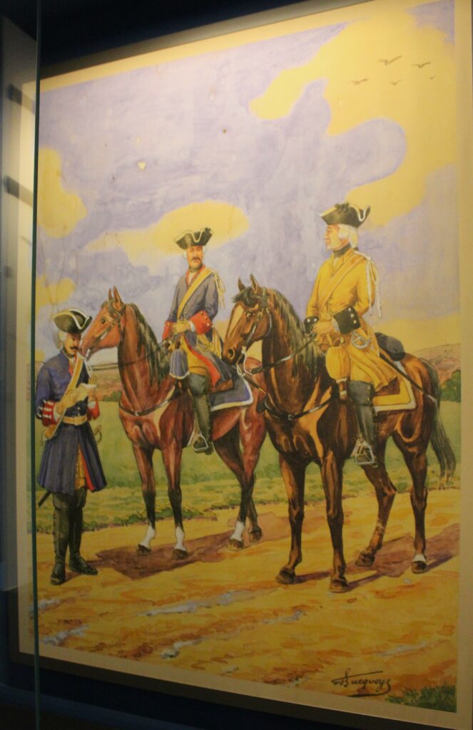 Un brigadier et deux cavaliers de la maréchaussée de Lorraine en 1740, peinture par le commandant Eugène Louis Bucquoy, officier de gendarmerie et uniformologue français ; œuvre conservée au musée de la Gendarmerie (Melun). Photographie en couleurs, prise de vue effectuée le jeudi 5 mars 2026. Crédits photographiques : © 2020 laromagne.info par Marie-Noëlle ESTIEZ BONHOMME.