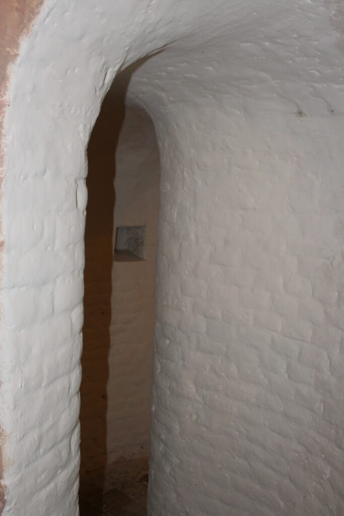 Entrée d’une « tournelle » de l'église Saint-Didier d'Asfeld (Ardennes), nom donné localement aux passages étroits ménagés dans l'épaisseur des murs. Ces coursières permettent de circuler tout autour de l'église sans traverser la nef. Photographies en couleurs, prises de vue réalisées le samedi 25 avril 2026. Crédits photographiques : © 2020 laromagne.info par Marie-Noëlle ESTIEZ BONHOMME.