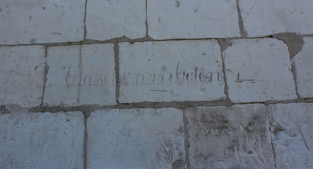 Pompe à eau de la ferme du château de Poilcourt-Sydney (Ardennes). L’inscription allemande « Waschen verboten » (« interdit de se laver »), encore visible sur l’ouvrage, constitue un témoignage matériel de l’occupation du village pendant la Première Guerre mondiale. Photographies en couleurs, prises de vue réalisées le samedi 25 avril 2026. Crédits photographiques : © 2020 laromagne.info par Marie-Noëlle ESTIEZ BONHOMME.