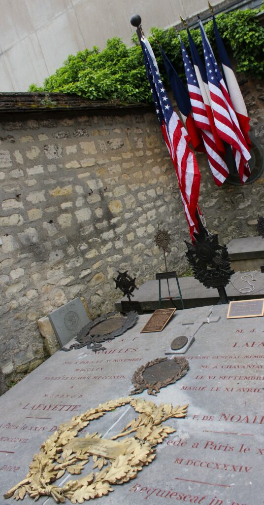 Sépulture au cimetière de Picpus (Paris, Île-de-France), lieu de mémoire associé au marquis de La Fayette et à l’histoire de l’indépendance des États-Unis. Dépôts de plaques et d’emblèmes en hommage aux combattants franco-américains. Photographie en couleurs, prise de vue réalisée le mercredi 20 mai 2026. Crédits photographiques : © 2020 laromagne.info par Marie-Noëlle ESTIEZ BONHOMME.